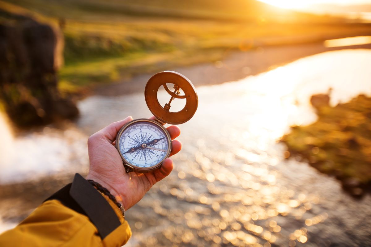 Beautiful landscape with old compass on traveler's hand